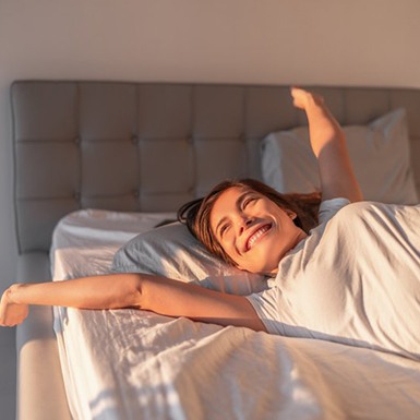 a woman smiling while waking up comfortably