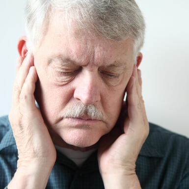 Man with migraine holding jaw in pain