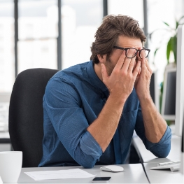 Tired man with head in hands at work