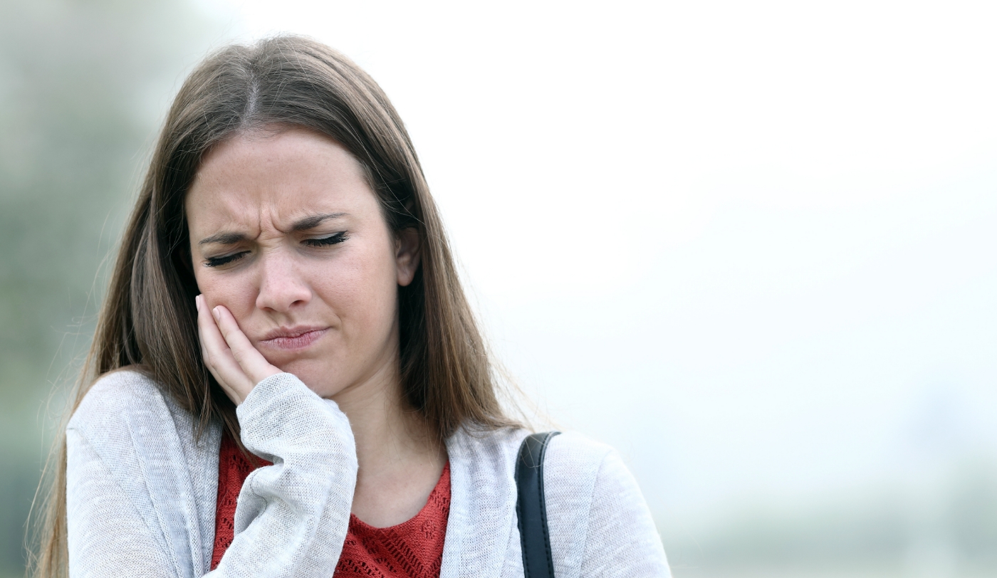Woman experiencing jaw pain caused by TMJ disorder