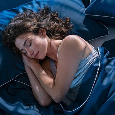 Woman sleeping peacefully in blue bedsheets