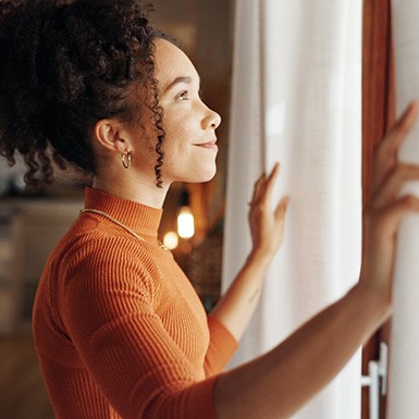 Woman opening her curtains in the morning