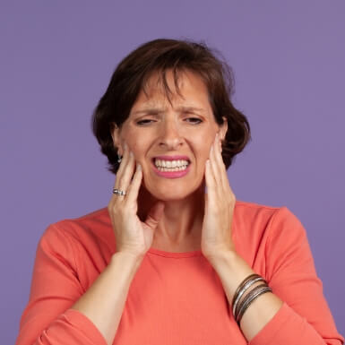 Woman with jaw pain holding her cheeks