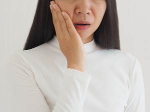 Close-up of woman in white shirt with TMJ disorder