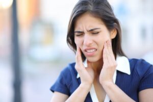 Young woman clutching jaw in pain. 