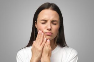 Woman holding jaw in pain. 
