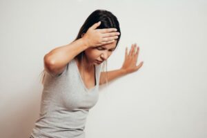 Woman leaning against a wall, experiencing vertigo 
