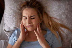 Woman lying in bed and rubbing her jaw